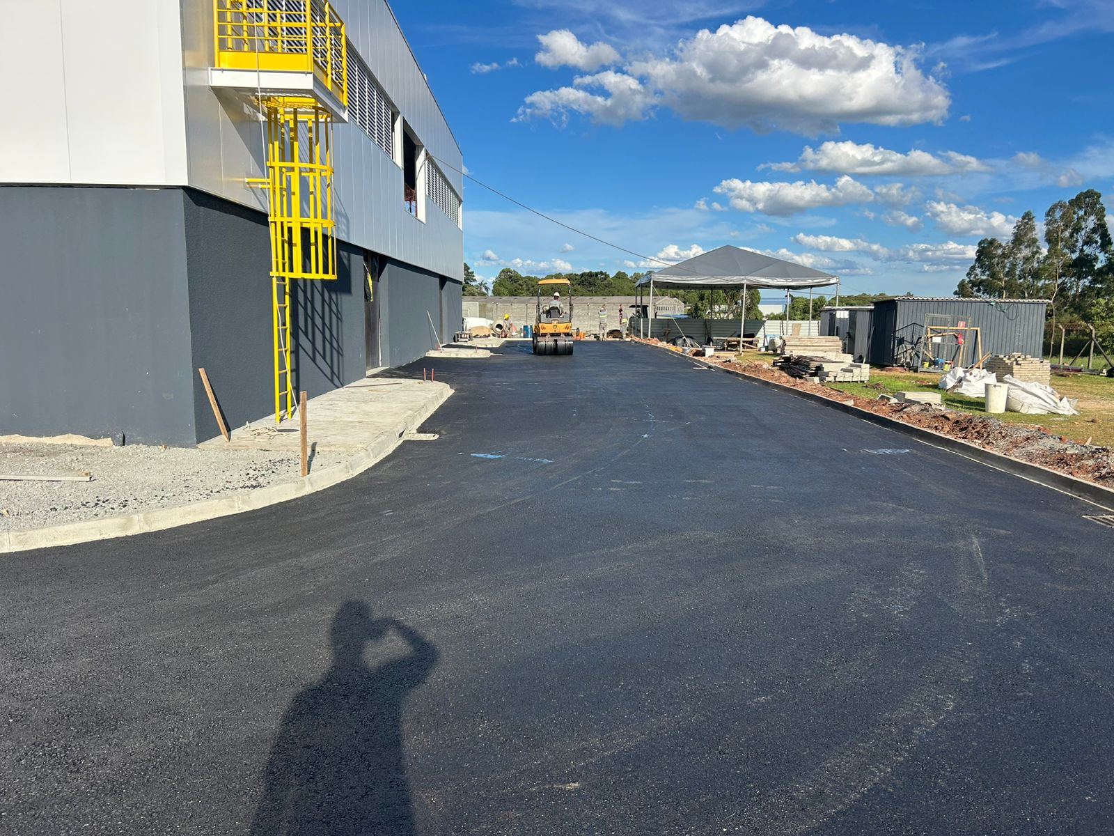 Freshly laid asphalt or concrete road surface with construction equipment and workers finishing the project